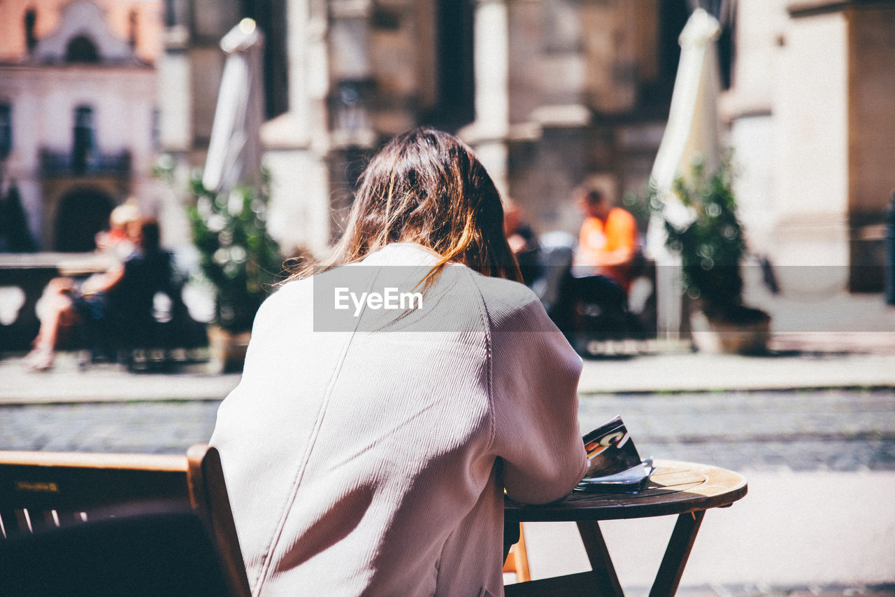 Rear view of woman sitting at sidewalk cafe