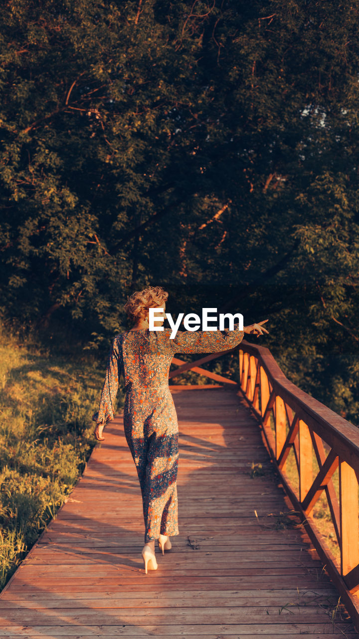 Rear view of woman walking on footbridge