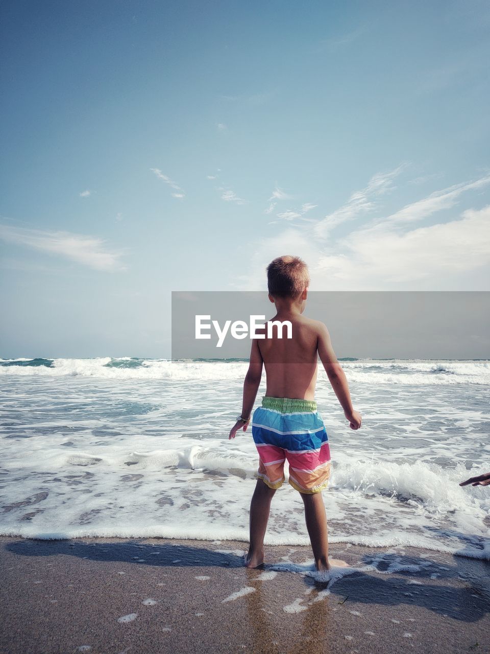 rear view full length of shirtless man standing at beach against sky