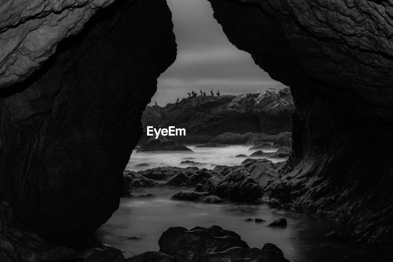 Rock formation on sea shore against sky