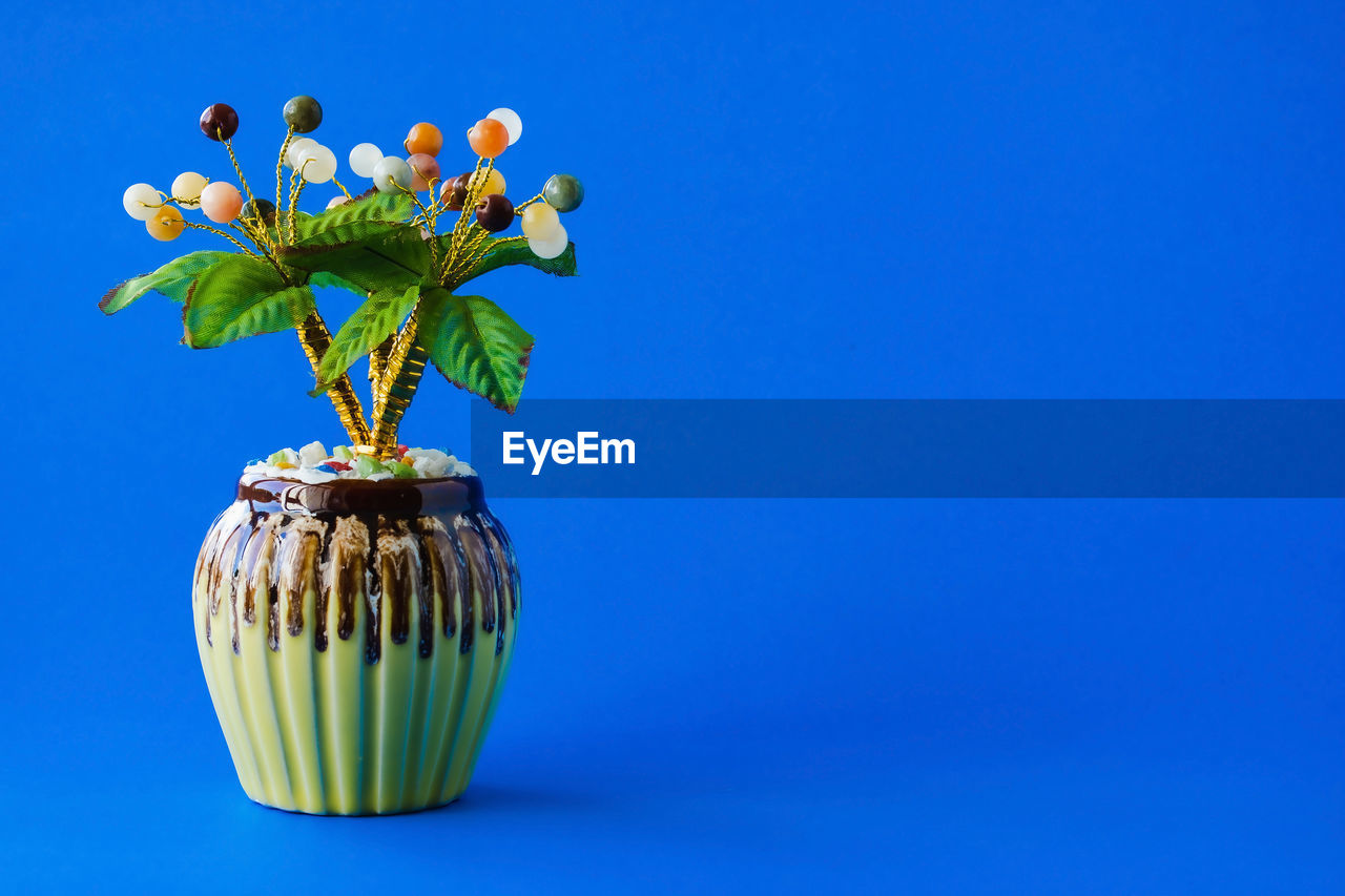 blue, plant, flower, flowering plant, nature, vase, yellow, blue background, studio shot, no people, indoors, colored background, freshness, copy space, beauty in nature, flower head, growth, flowerpot, fragility, leaf, food, plant part, green, decoration, close-up, food and drink