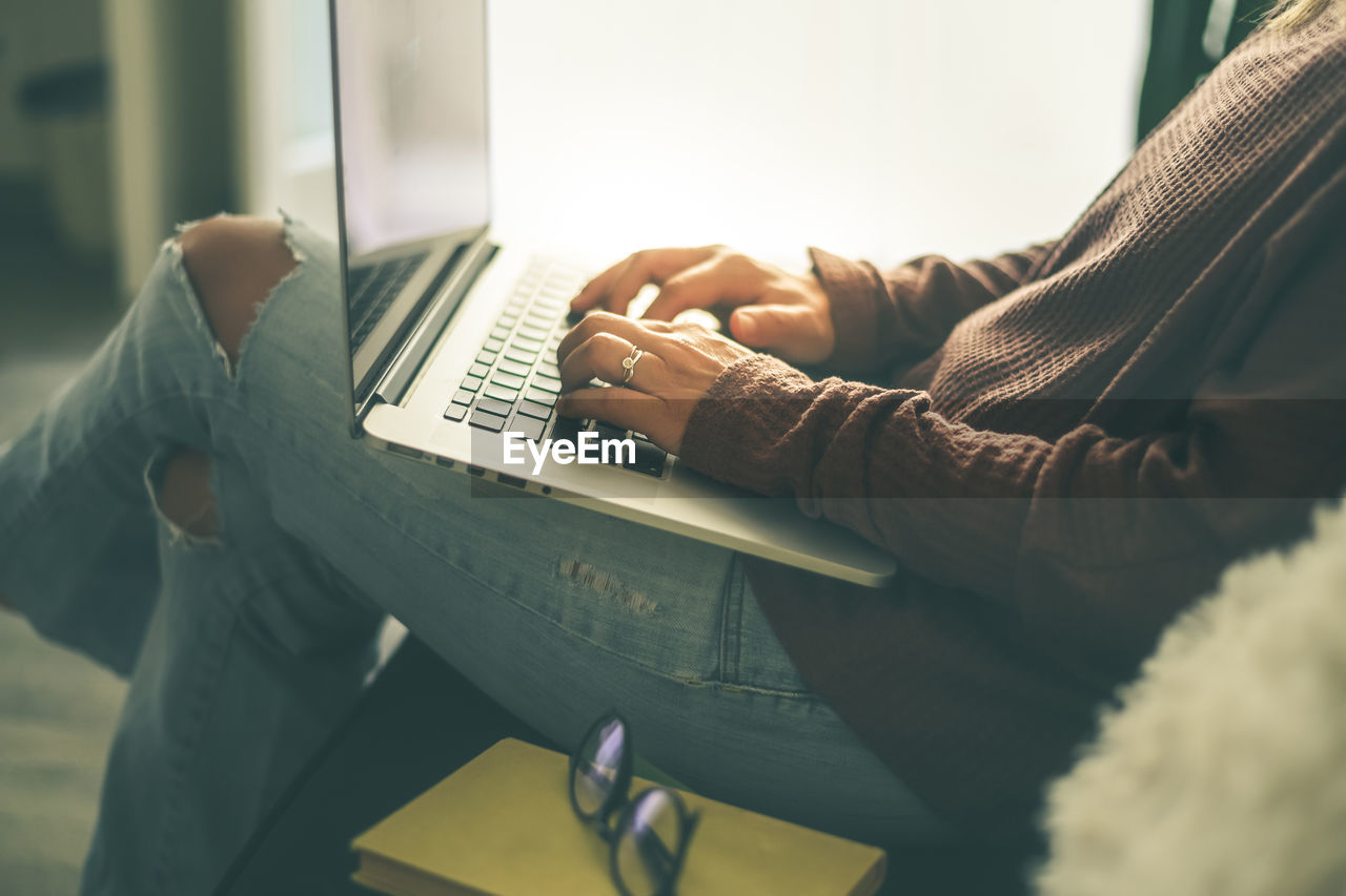 Young woman working on laptop at home. closeup of female hands typing on pc keyboard teenager using