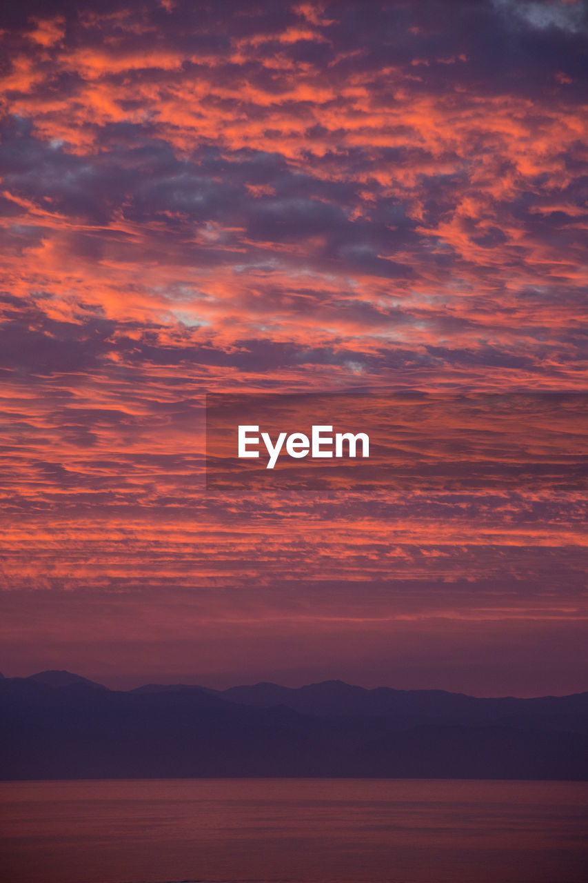 SCENIC VIEW OF SEA AGAINST DRAMATIC SKY DURING SUNSET