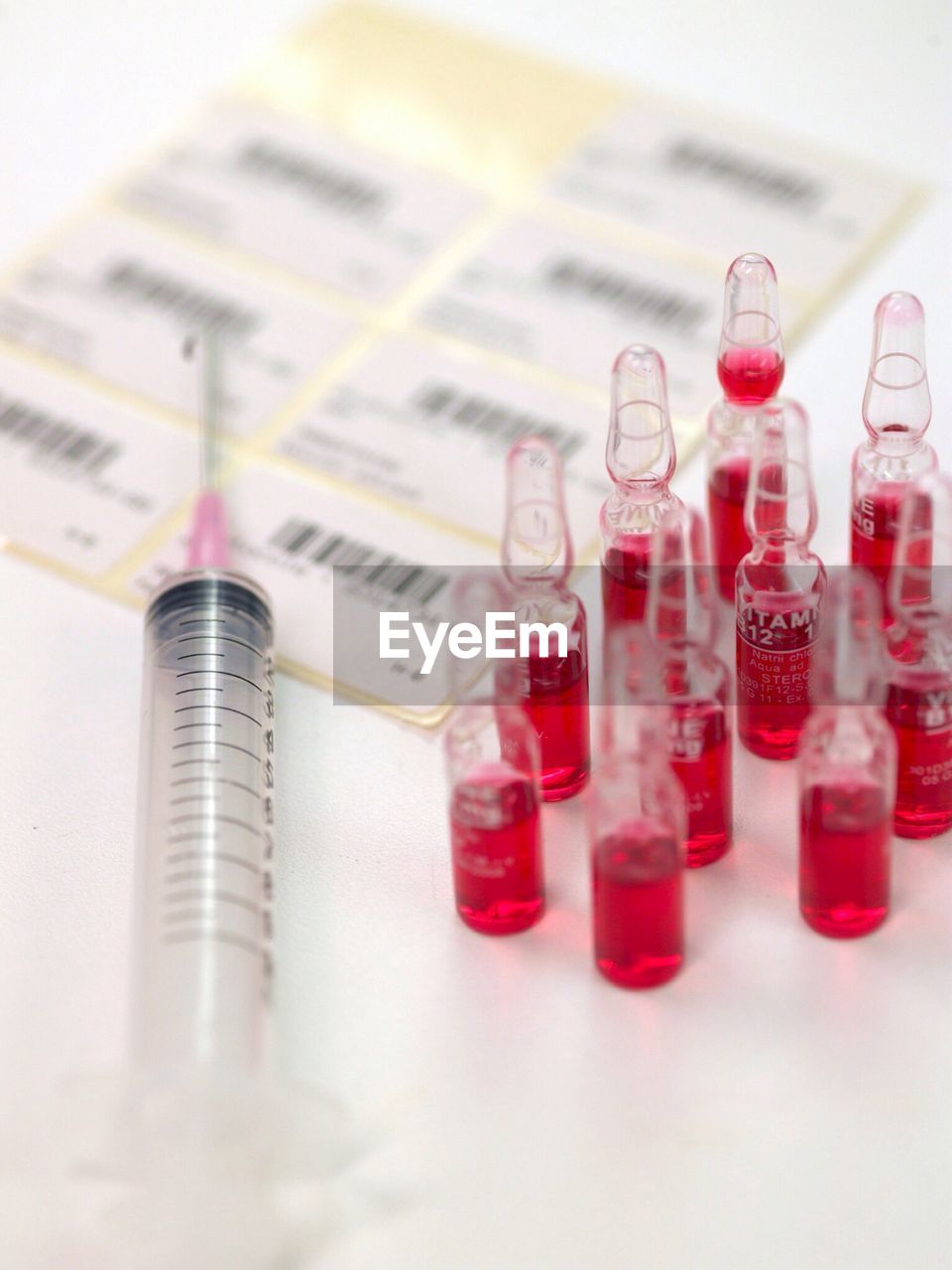 Close-up of syringe with bar codes and vitamin bottles