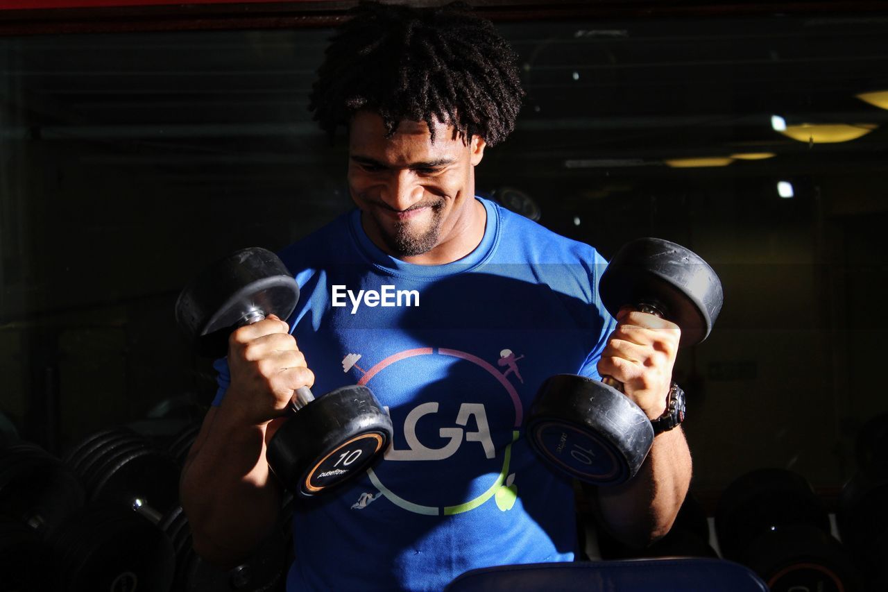 Young man lifting dumbbells in gym