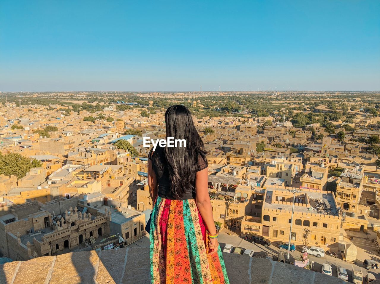 Rear view of woman looking at cityscape against sky