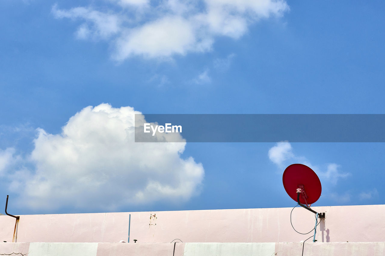 Red satellite dish on brick wall