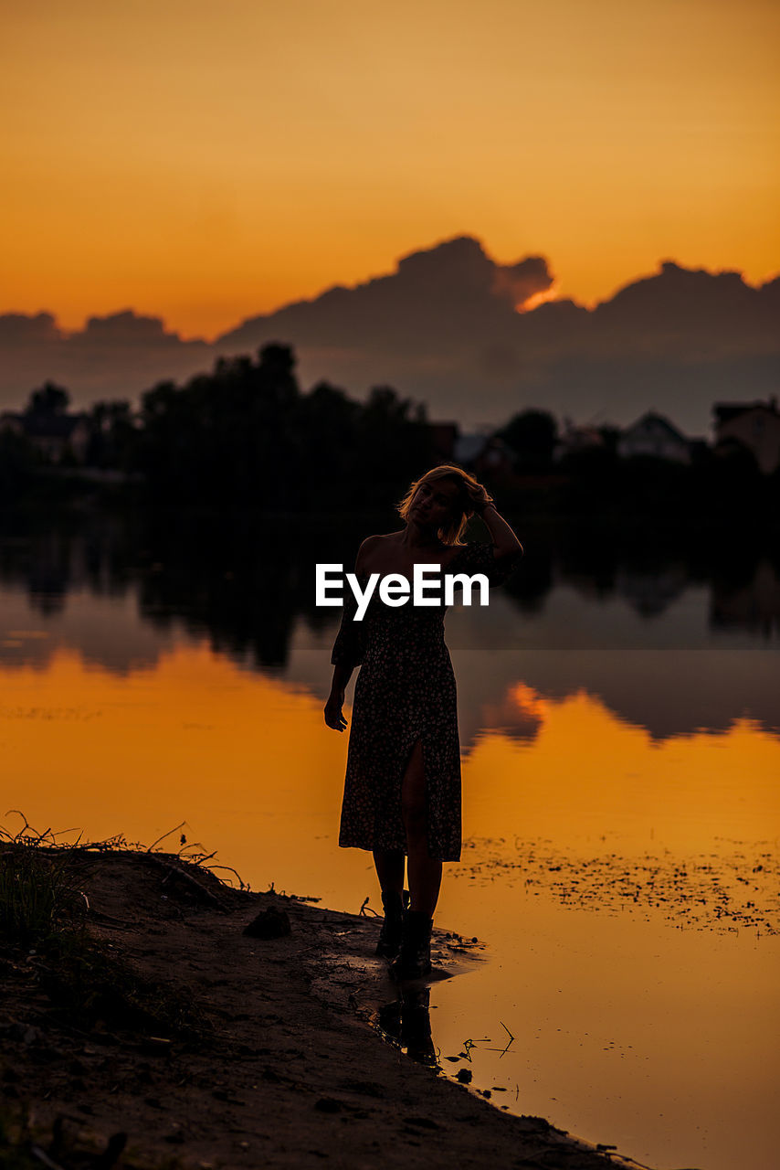 Silhouette woman standing on field against sky during sunset