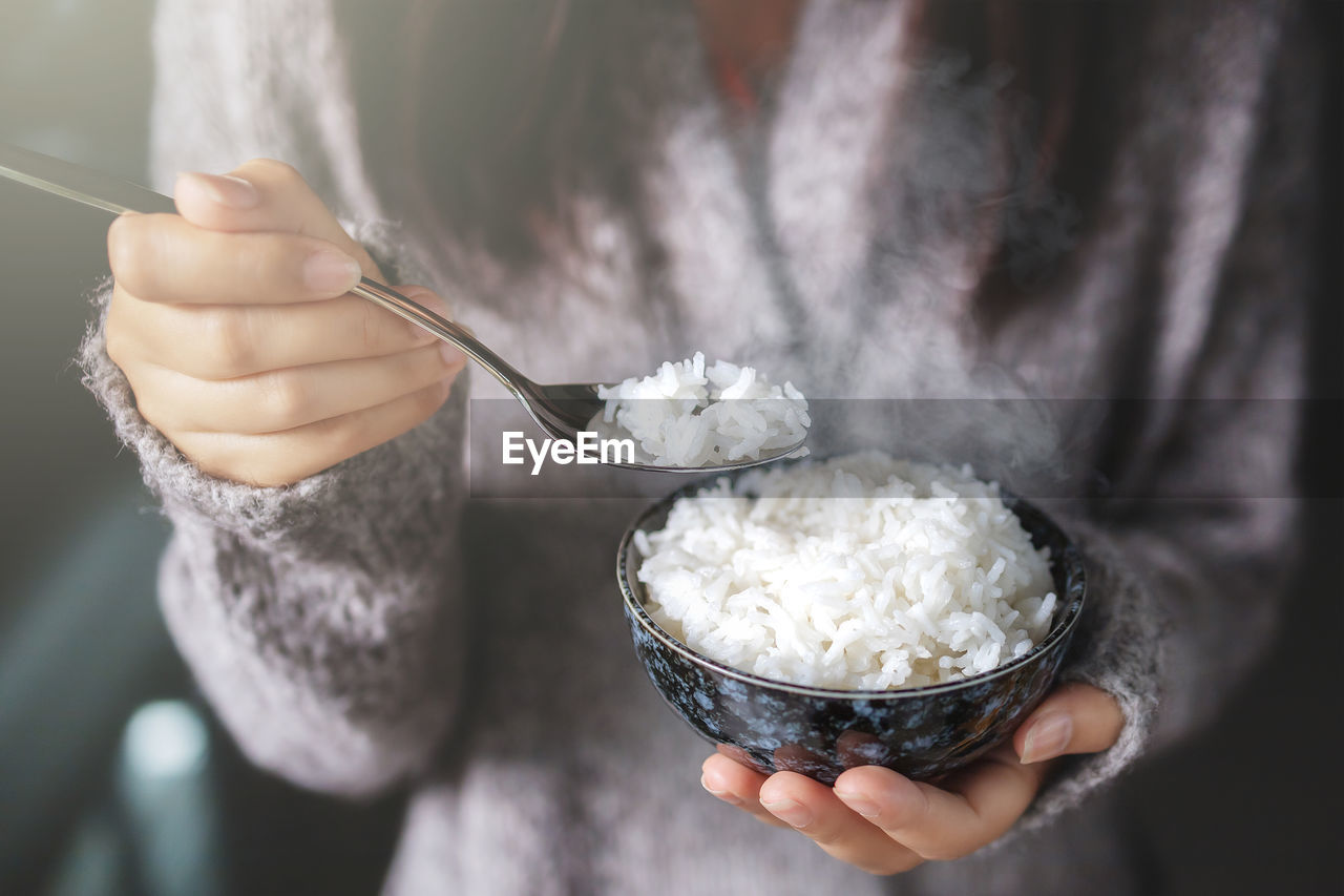 Midsection of woman holding rice in bowl