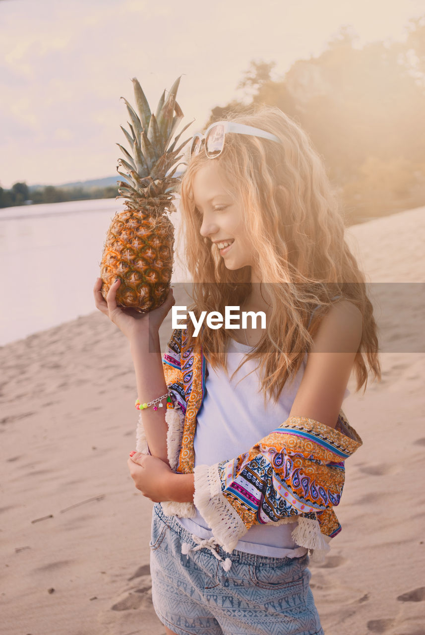 Girl holding pineapple on beach