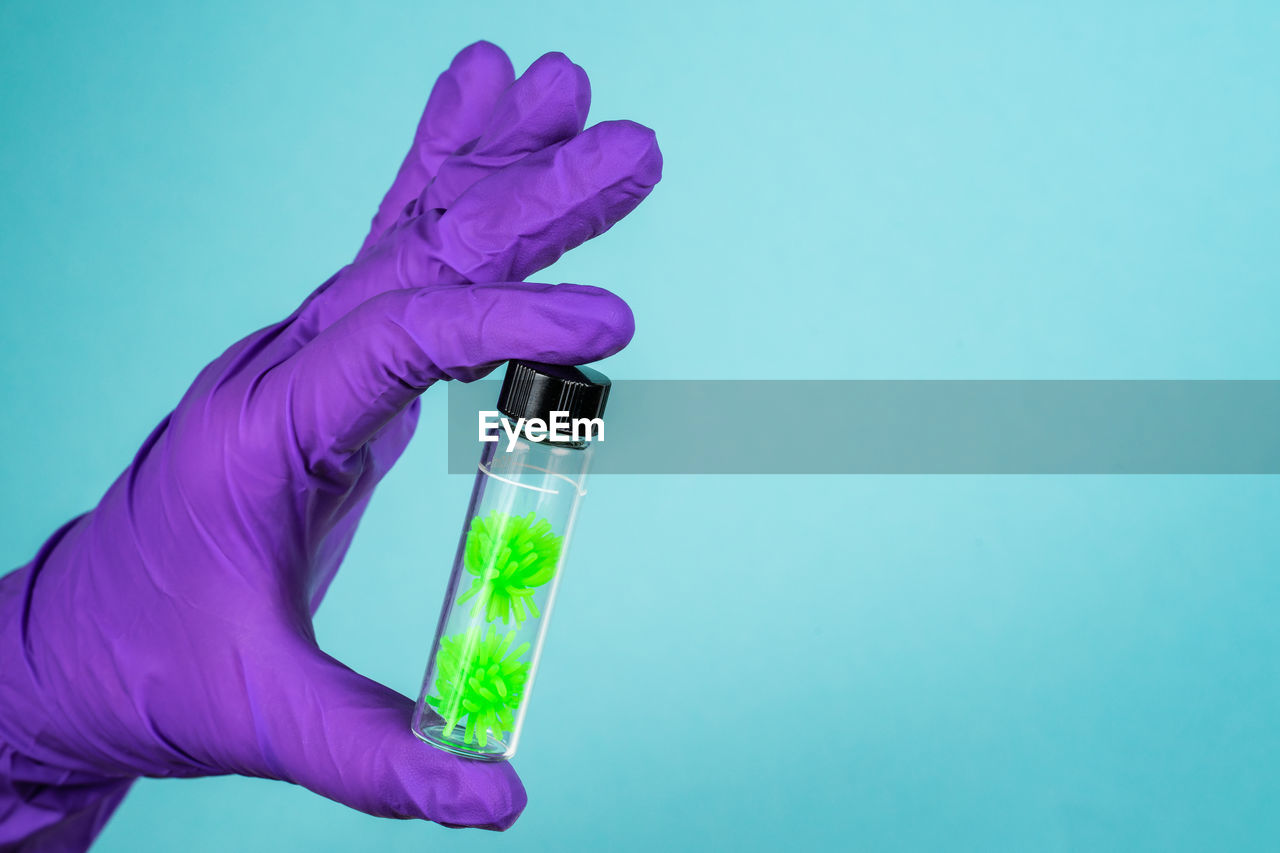 CROPPED IMAGE OF HAND HOLDING BLUE COLORED BACKGROUND