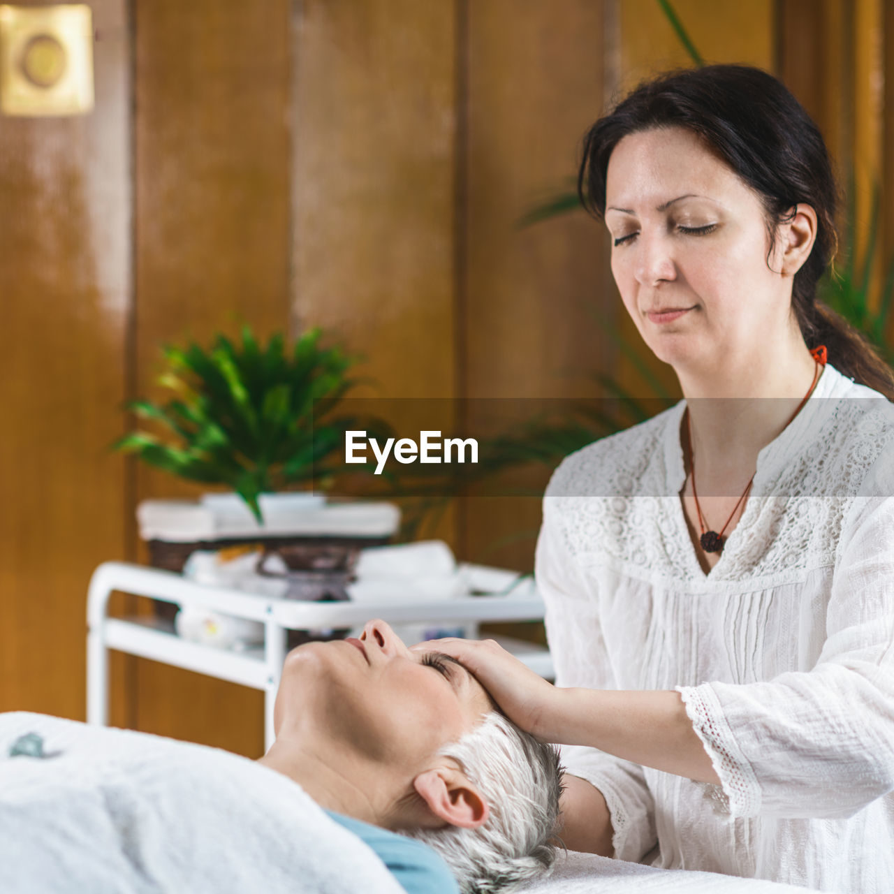 Smiling woman giving massage to client at spa