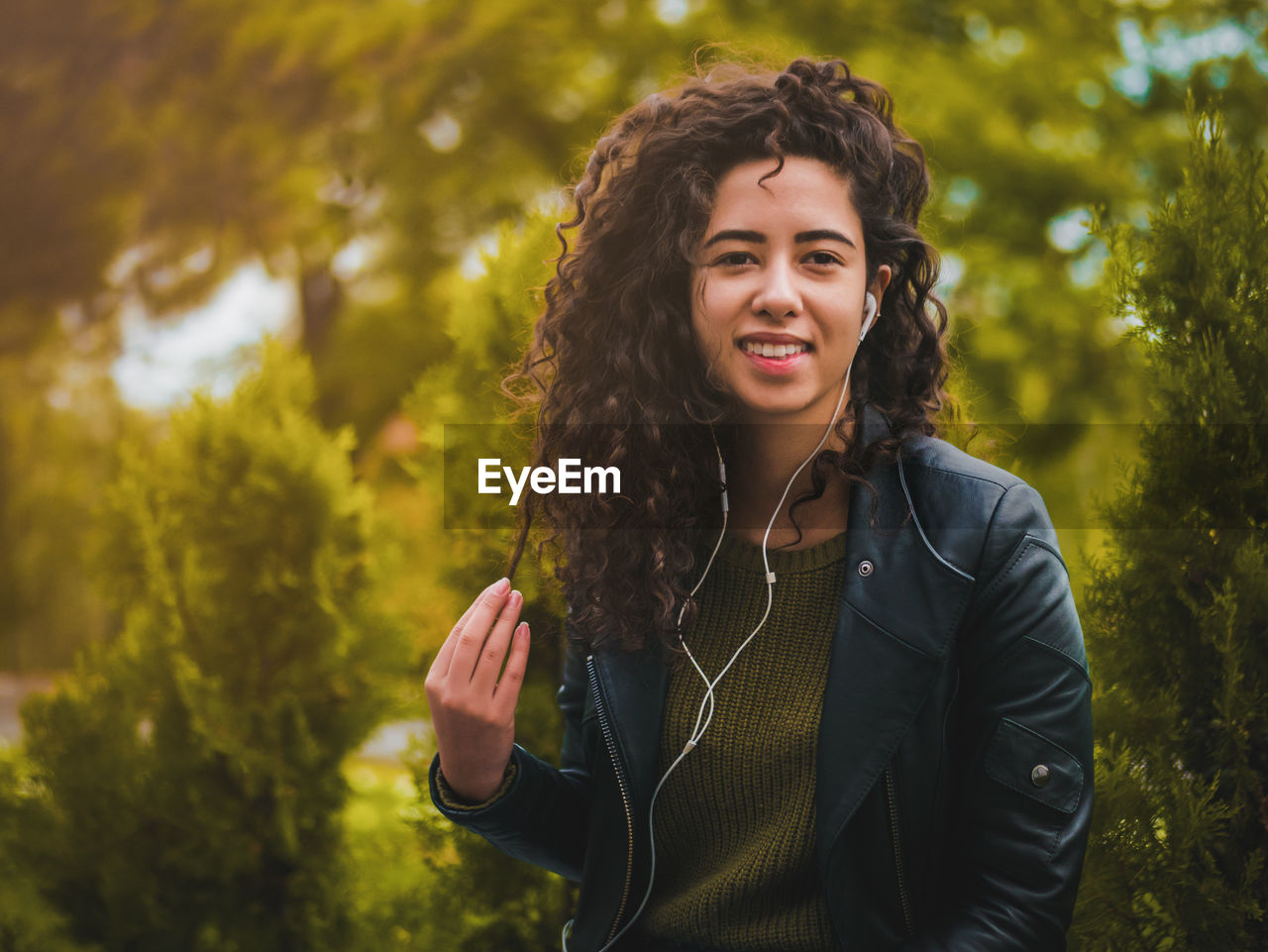 Portrait of young woman listening to music by plants