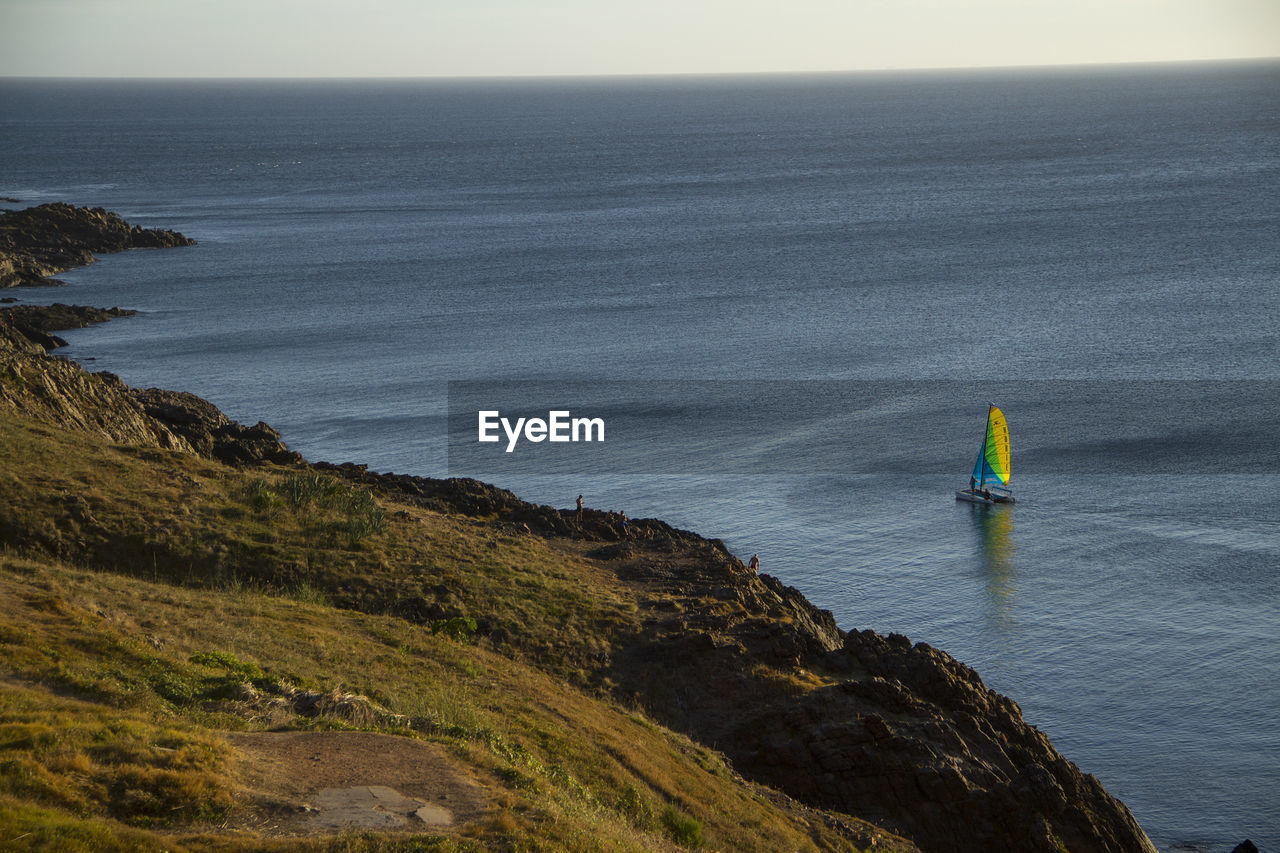 HIGH ANGLE VIEW OF SEA BY ROCKS AGAINST SKY