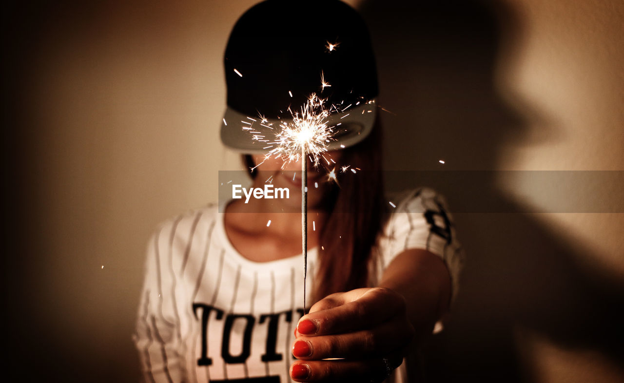 Woman holding sparkler indoors