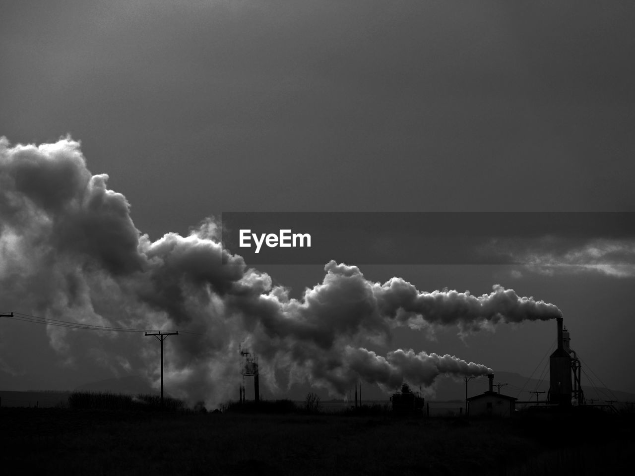 Industrial smoke stacks emitting pollution against sky