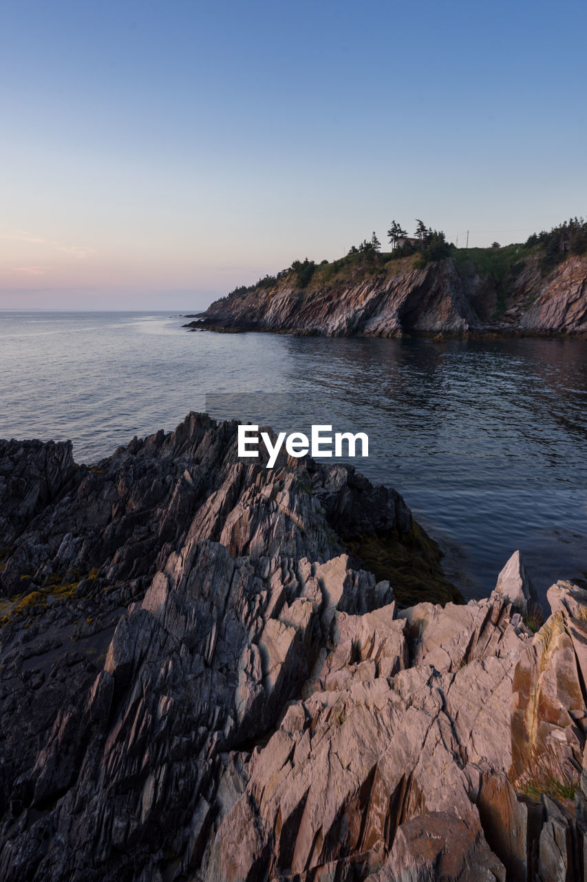 Scenic view of rocks in sea against clear sky