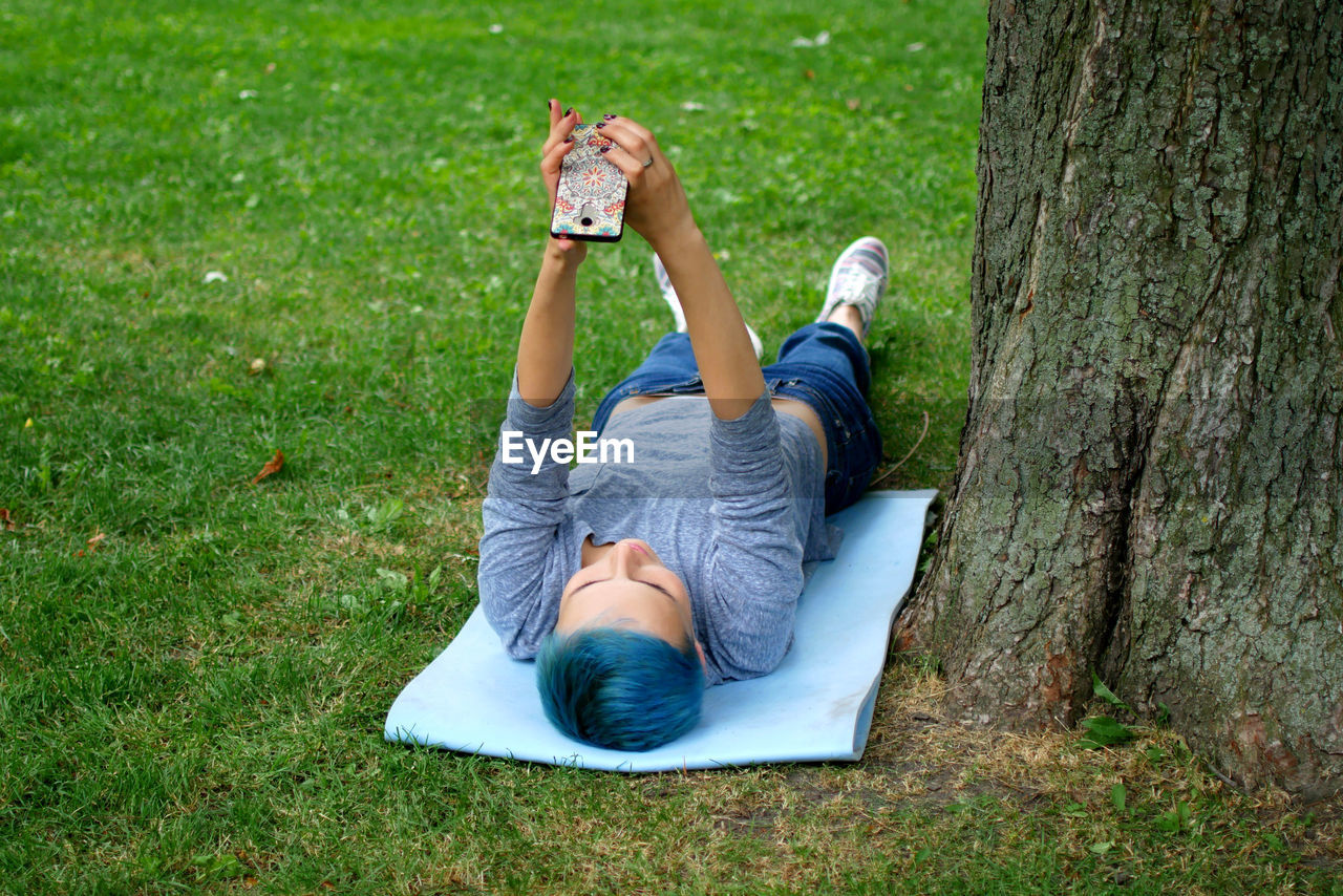 High angle view of woman taking selfie while lying in park