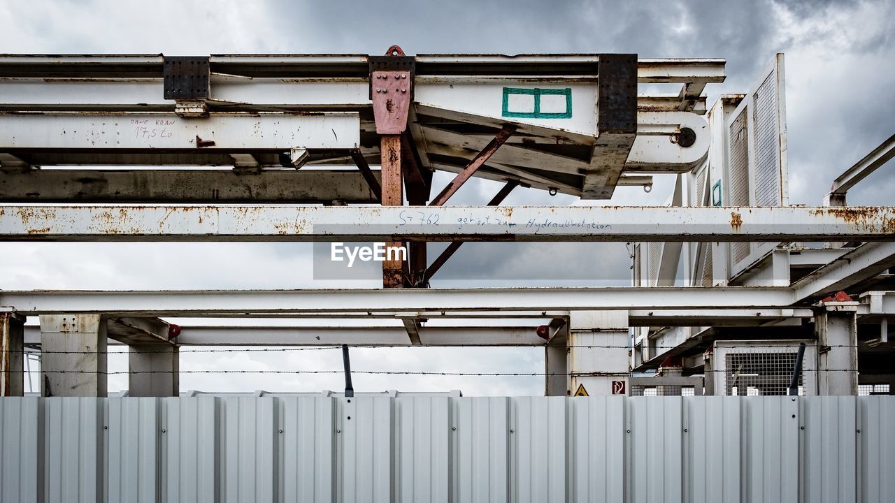 Low angle view of industry by building against sky