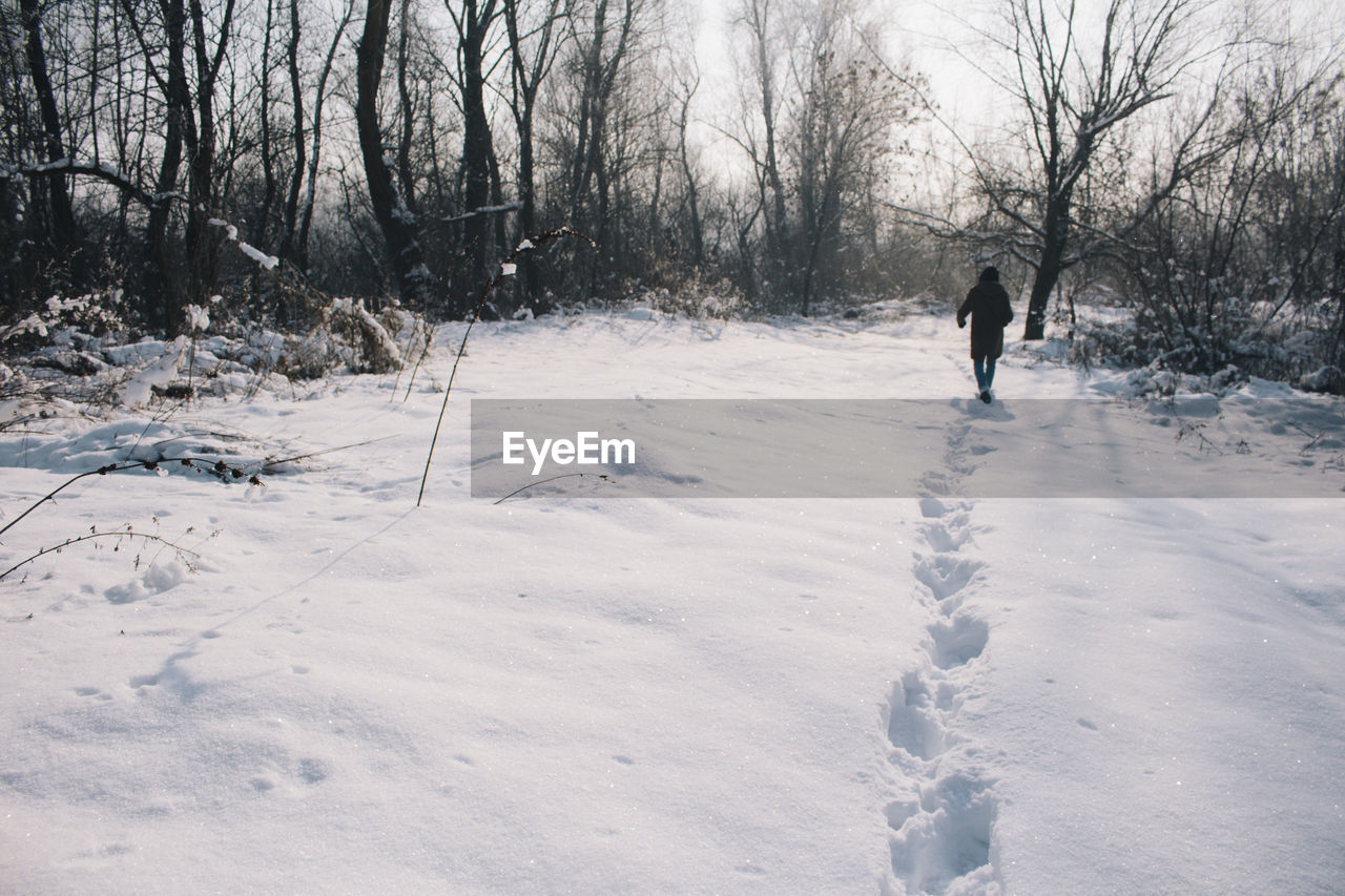 MAN WALKING ON SNOWY FIELD