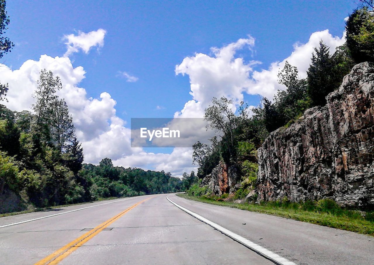 Empty road with trees in background