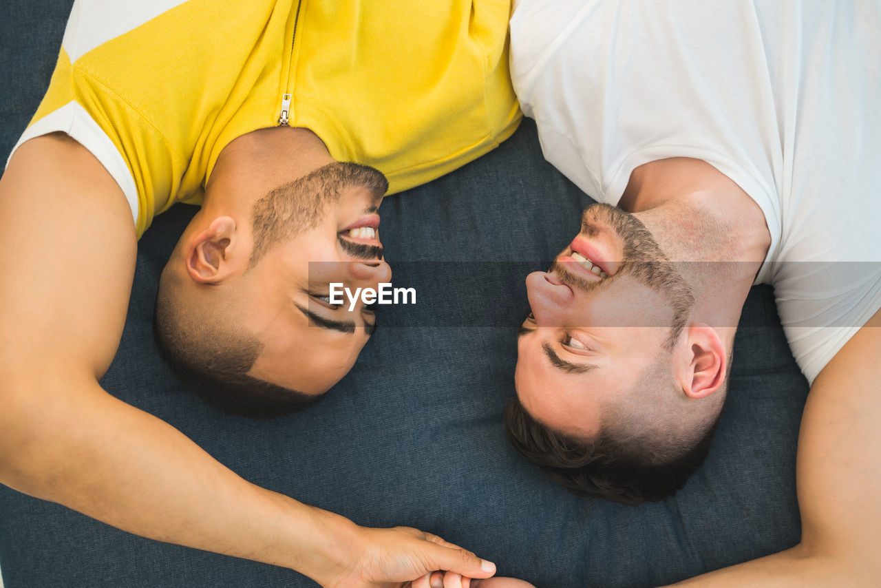 High angle view of gay couple lying down bed