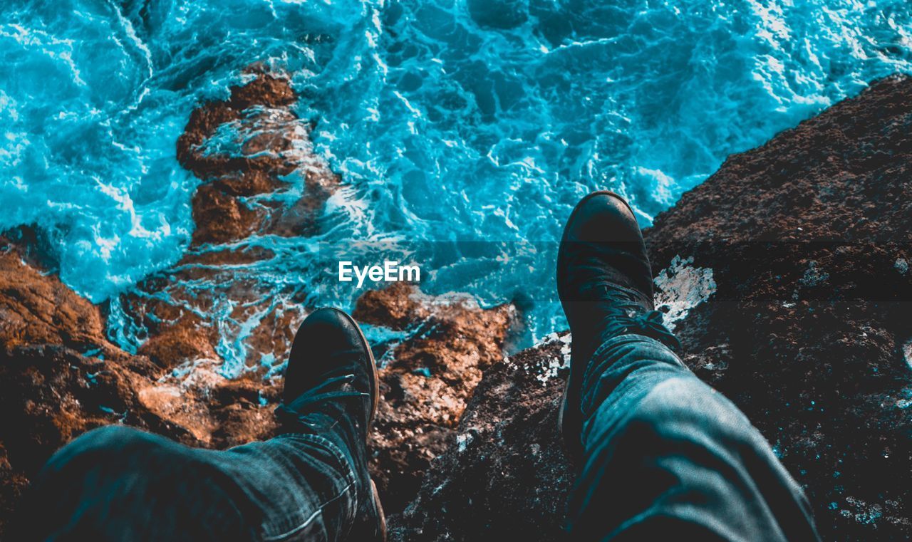 Low section of man on rock against sea