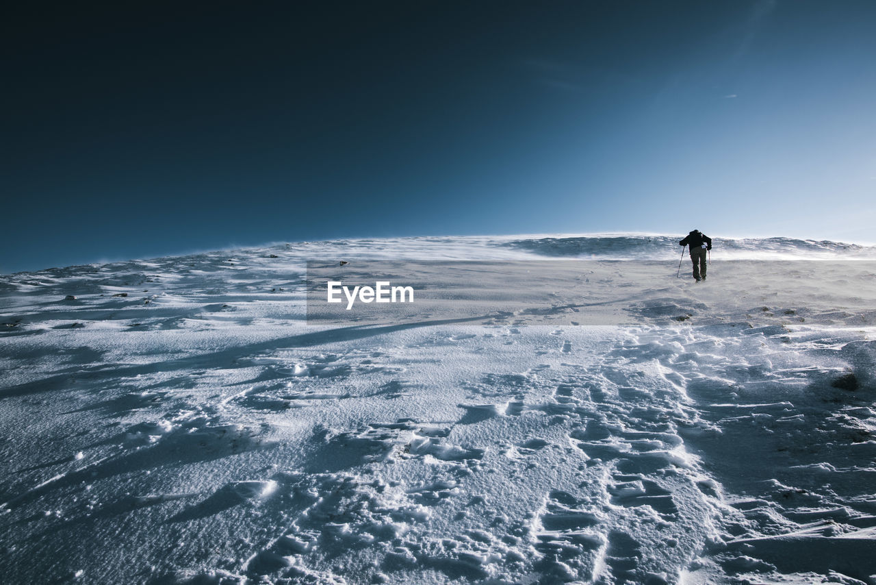 Man skiing on snowcapped mountain against clear sky