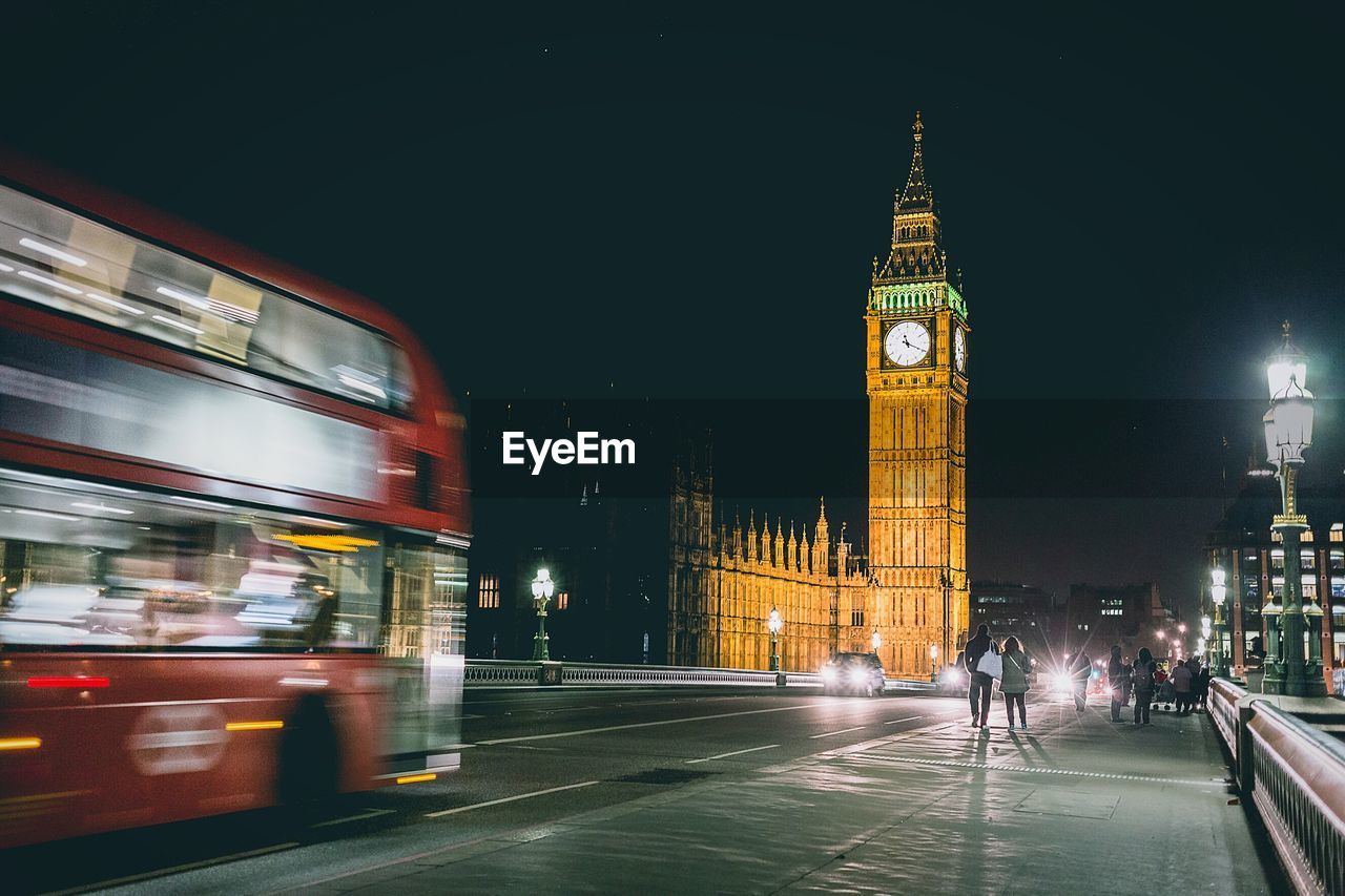 Rear view of people on westminster bridge by big ben in city at night