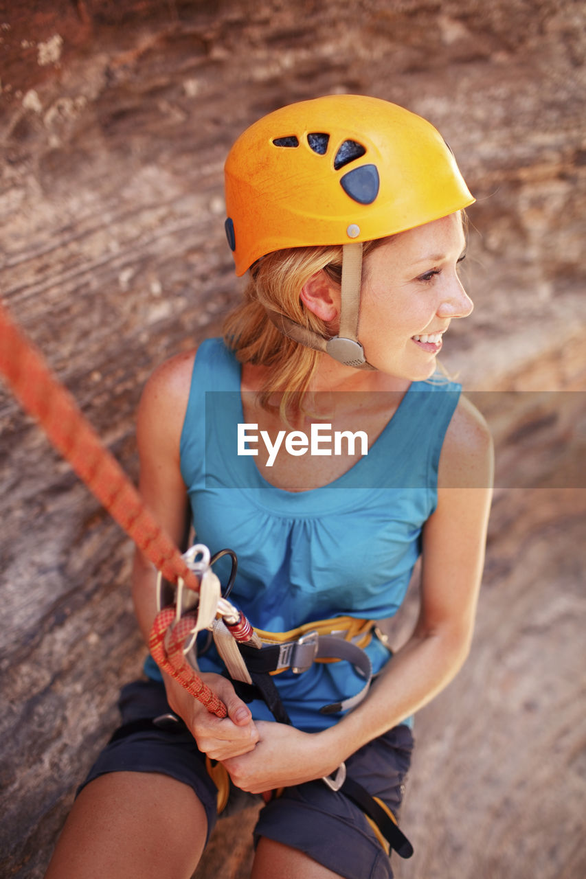 Smiling woman hanging on climbing rope during hiking