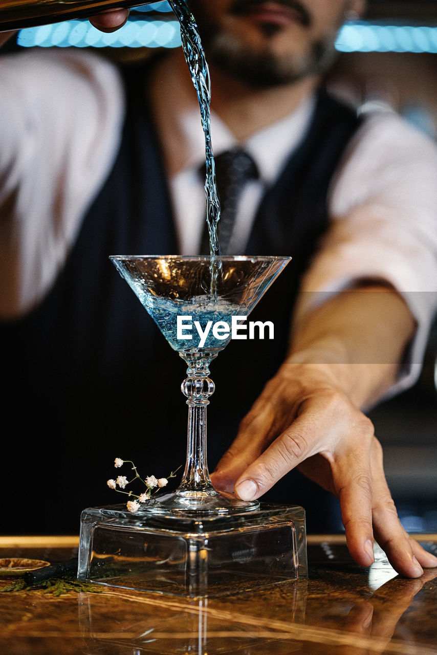 LOW ANGLE VIEW OF MAN POURING GLASS IN WINEGLASS