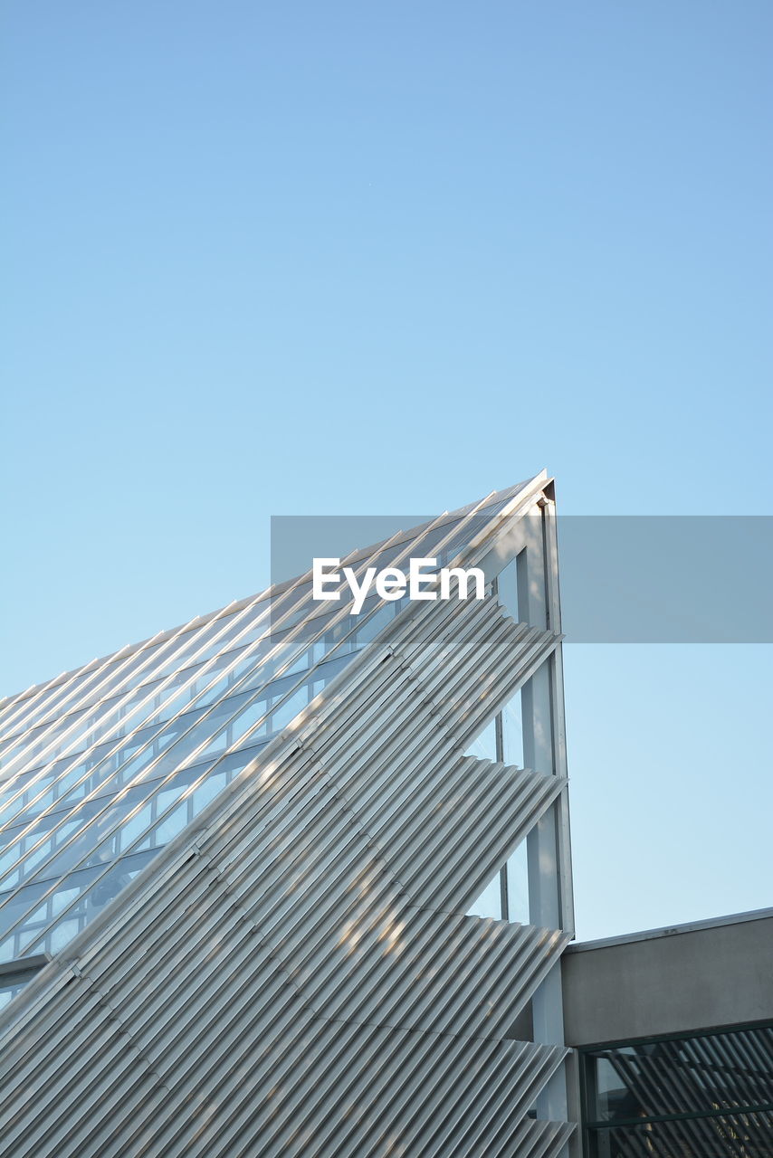 Low angle view of modern building against clear blue sky