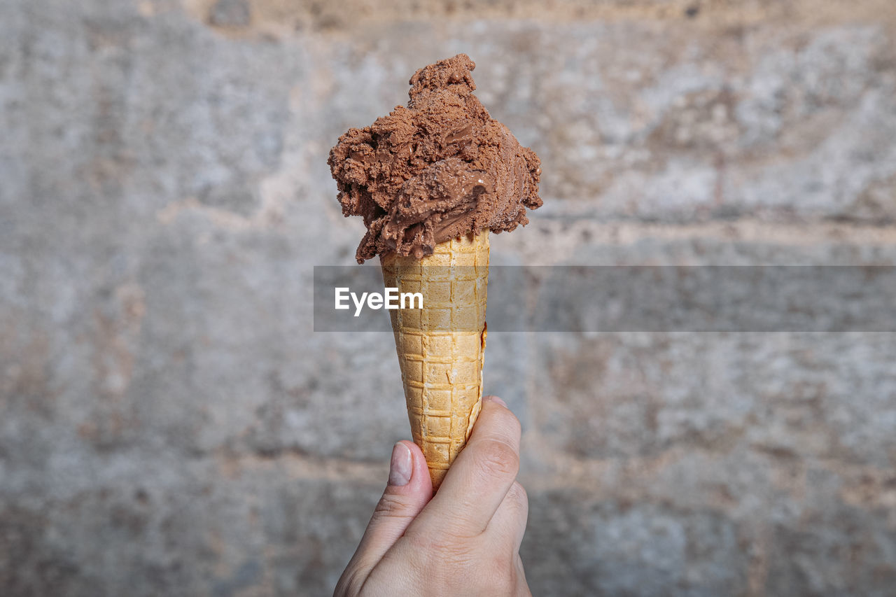 Hand holding chocolate ice cream cone. chocolate ice cream in waffle cone