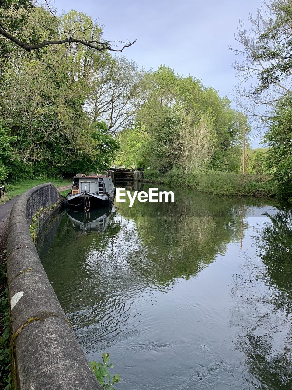 BOAT MOORED BY RIVER AGAINST SKY