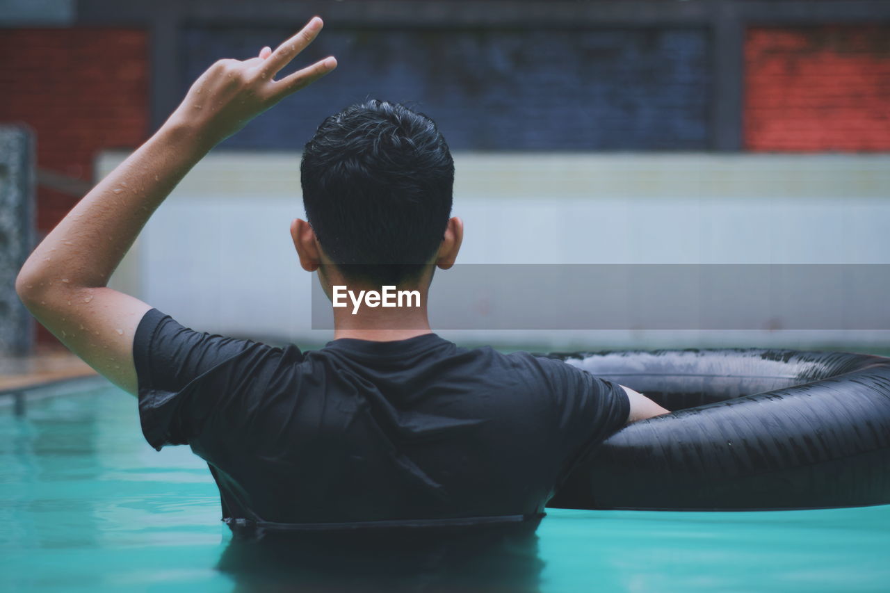 Young man gesturing peace sign in swimming pool