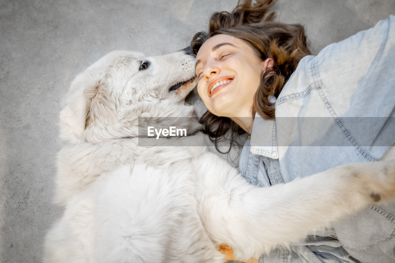 Smiling woman lying on floor with dog at home