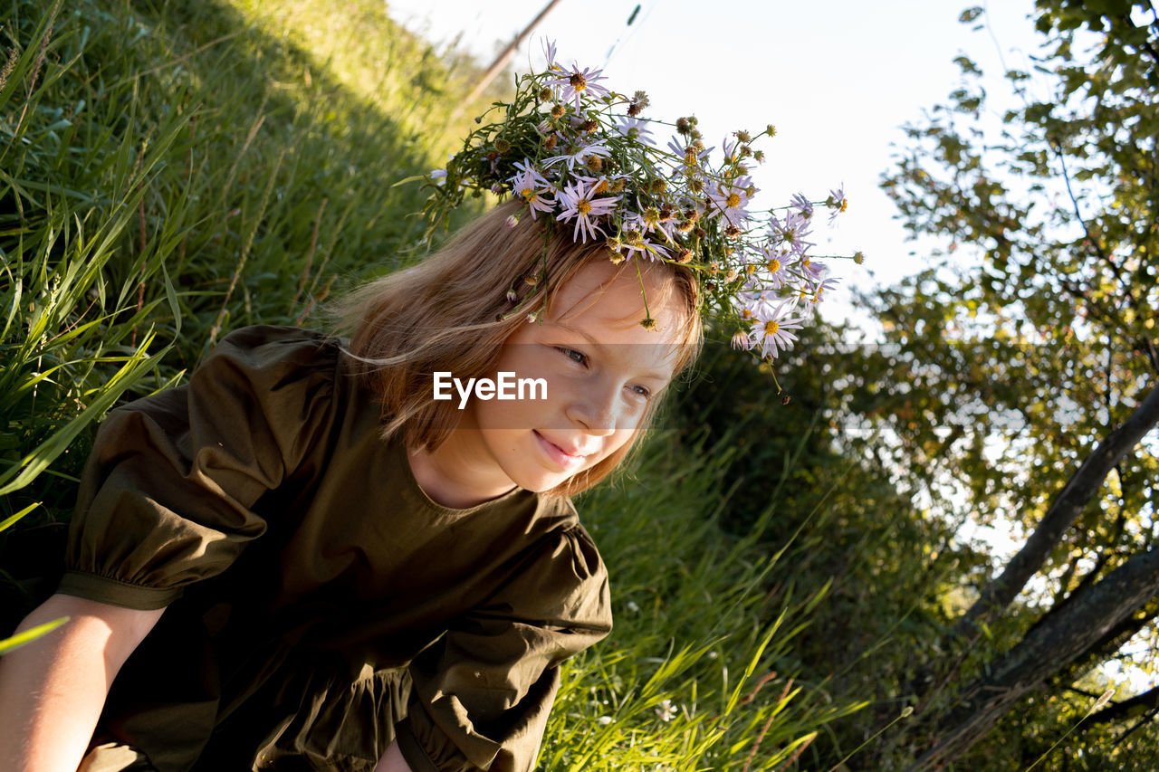 Child with a wreath on his head. girl in a dress and a straw hat. glade with flowers. 