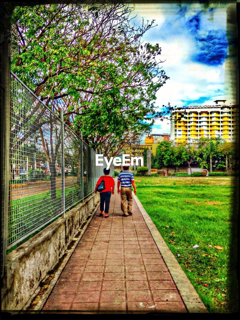 REAR VIEW OF MAN WALKING ON FOOTPATH AGAINST TREES