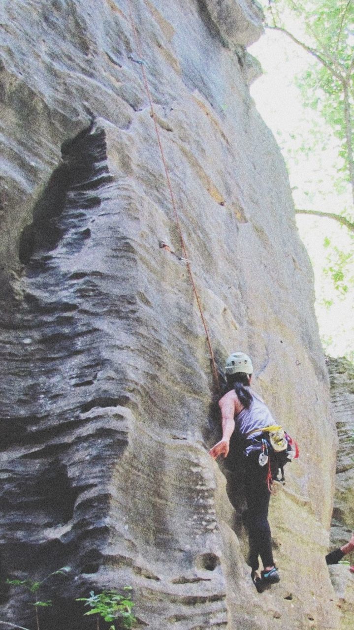 FULL LENGTH OF MAN CLIMBING ROCK