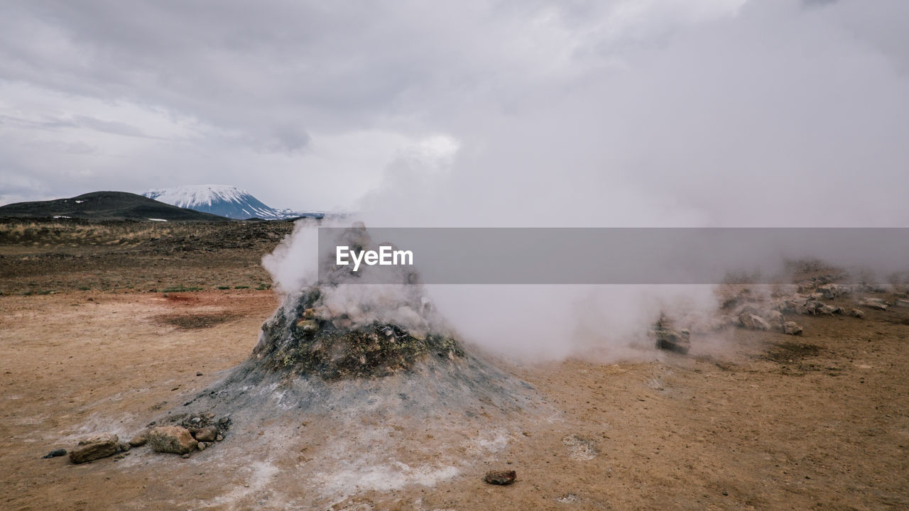 Steam emitting from volcano against cloudy sky
