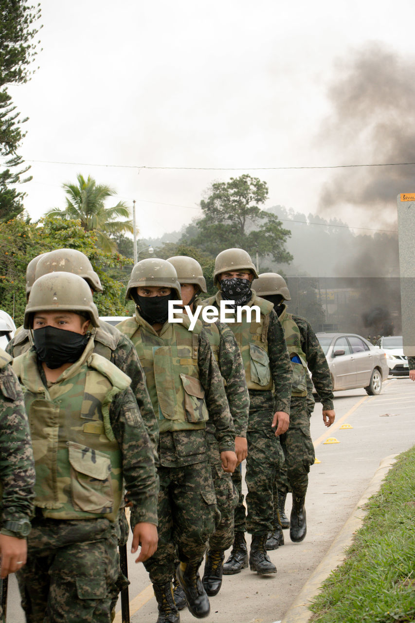 Soldiers wearing uniform walking on road in city