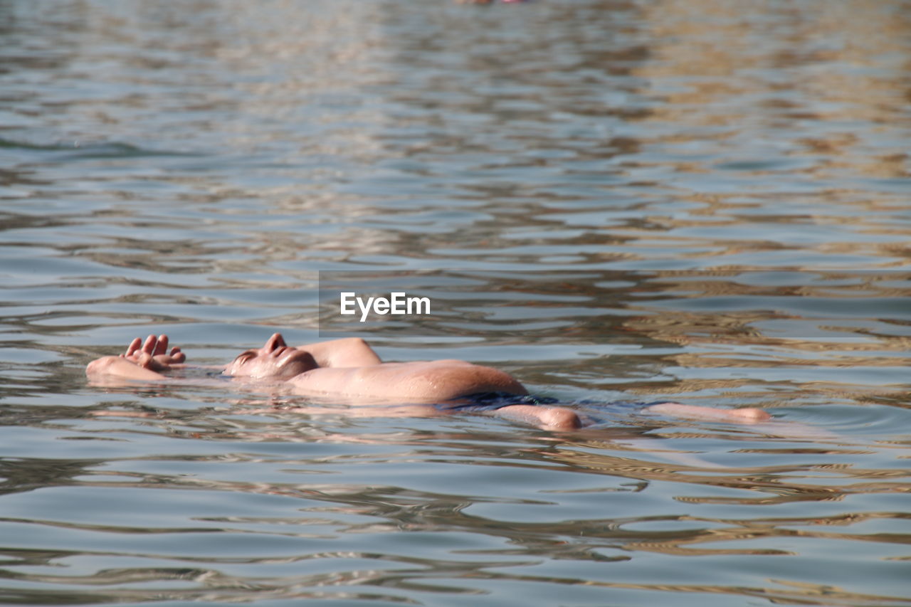Shirtless man floating on water in lake