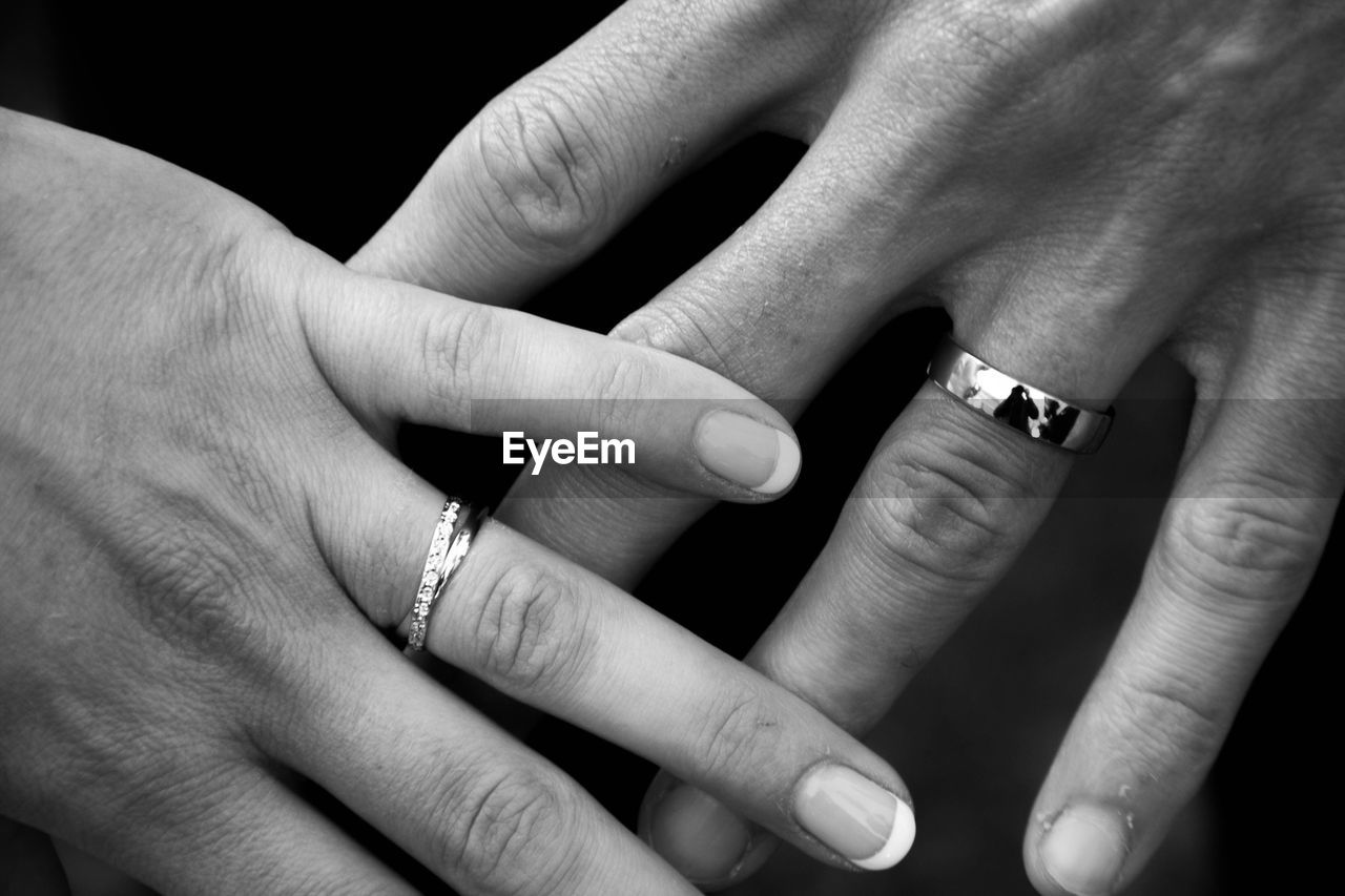 Cropped hands of bride and groom showing wedding rings