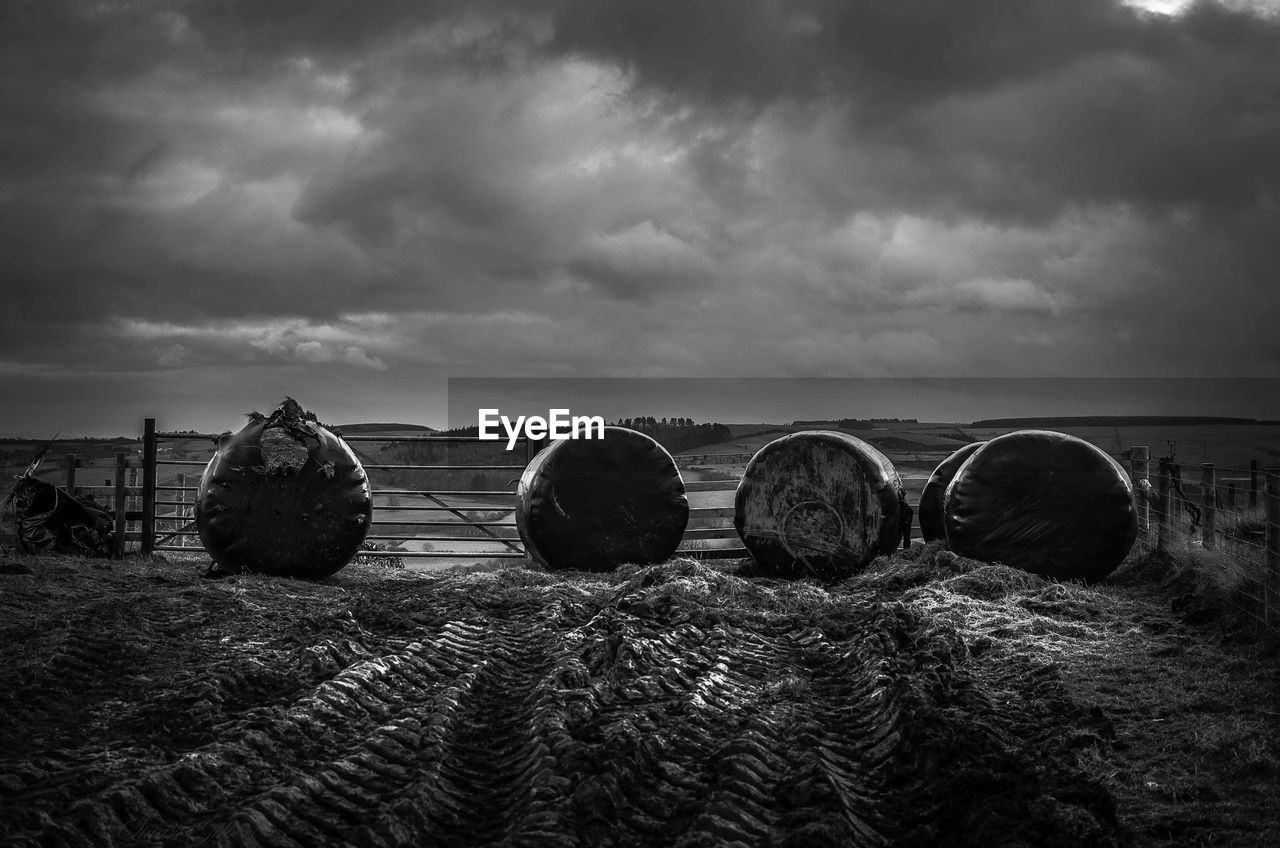 cloud, sky, bale, darkness, hay, black and white, monochrome, agriculture, land, landscape, monochrome photography, environment, nature, farm, rural scene, black, field, harvesting, plant, no people, scenics - nature, tranquility, horizon, crop, tranquil scene, outdoors, in a row, overcast, sunlight, dramatic sky, beauty in nature, dark, rolled up