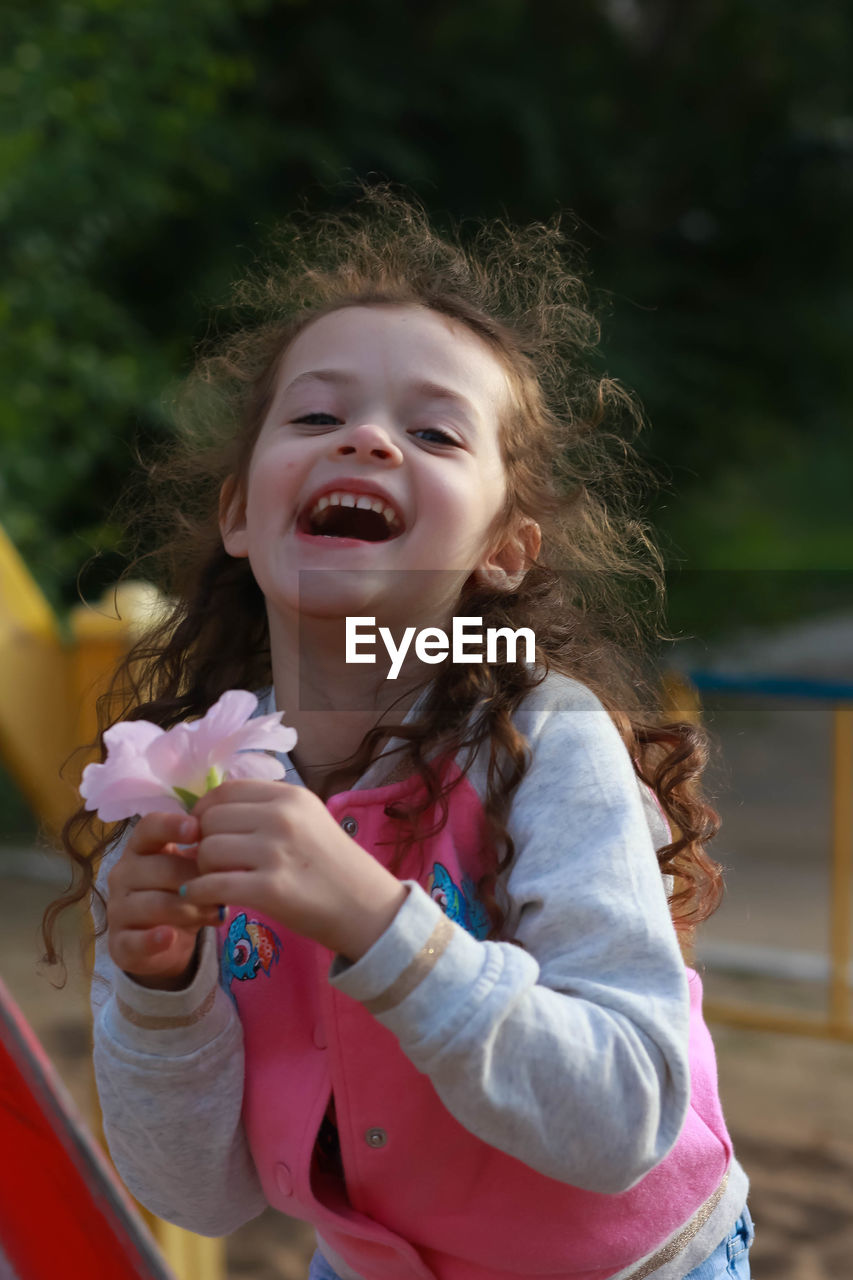 Portrait of happy girl holding flowers in park