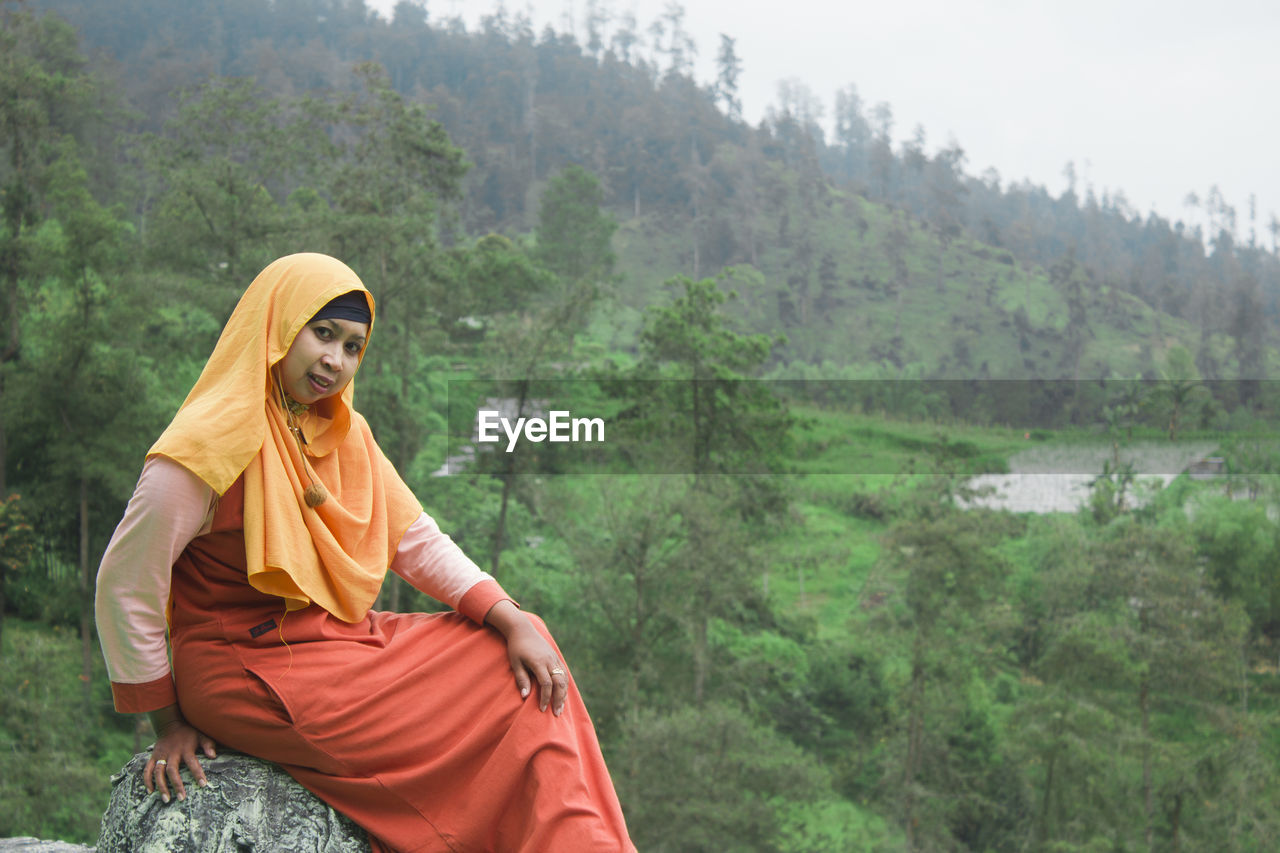 Close up photo of a woman outdoors with a green forest view