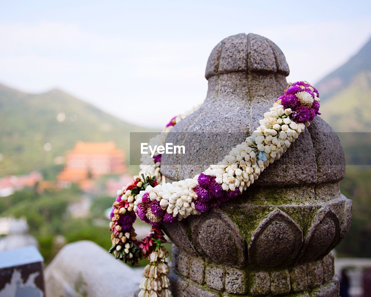 Close-up of garland on stone bollard against sky