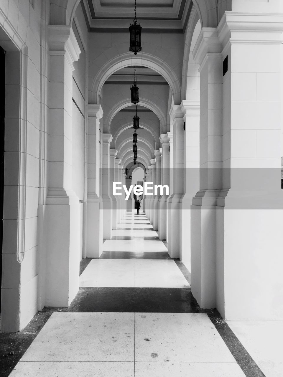 REAR VIEW OF MAN WALKING IN CORRIDOR OF BUILDING