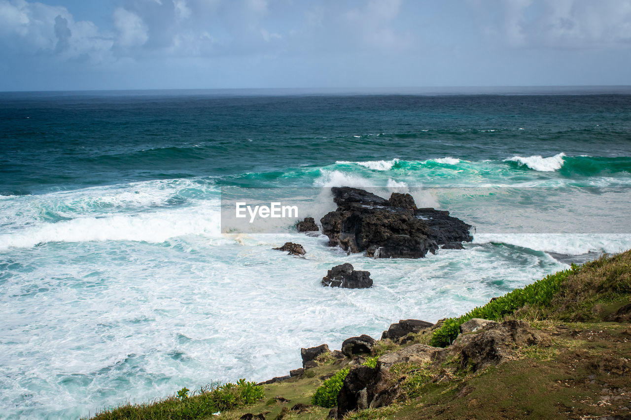sea, water, land, beach, body of water, sky, shore, ocean, beauty in nature, scenics - nature, rock, wave, horizon over water, horizon, wind wave, coast, nature, motion, cloud, cliff, surfing, sports, water sports, cove, coastline, environment, travel destinations, terrain, bay, outdoors, travel, vacation, tranquility, day, seascape, islet, idyllic, tranquil scene, landscape, tourism, non-urban scene, rock formation, blue, tropical climate, trip, holiday