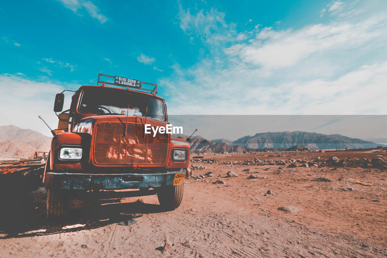 Truck on mountain against cloudy sky